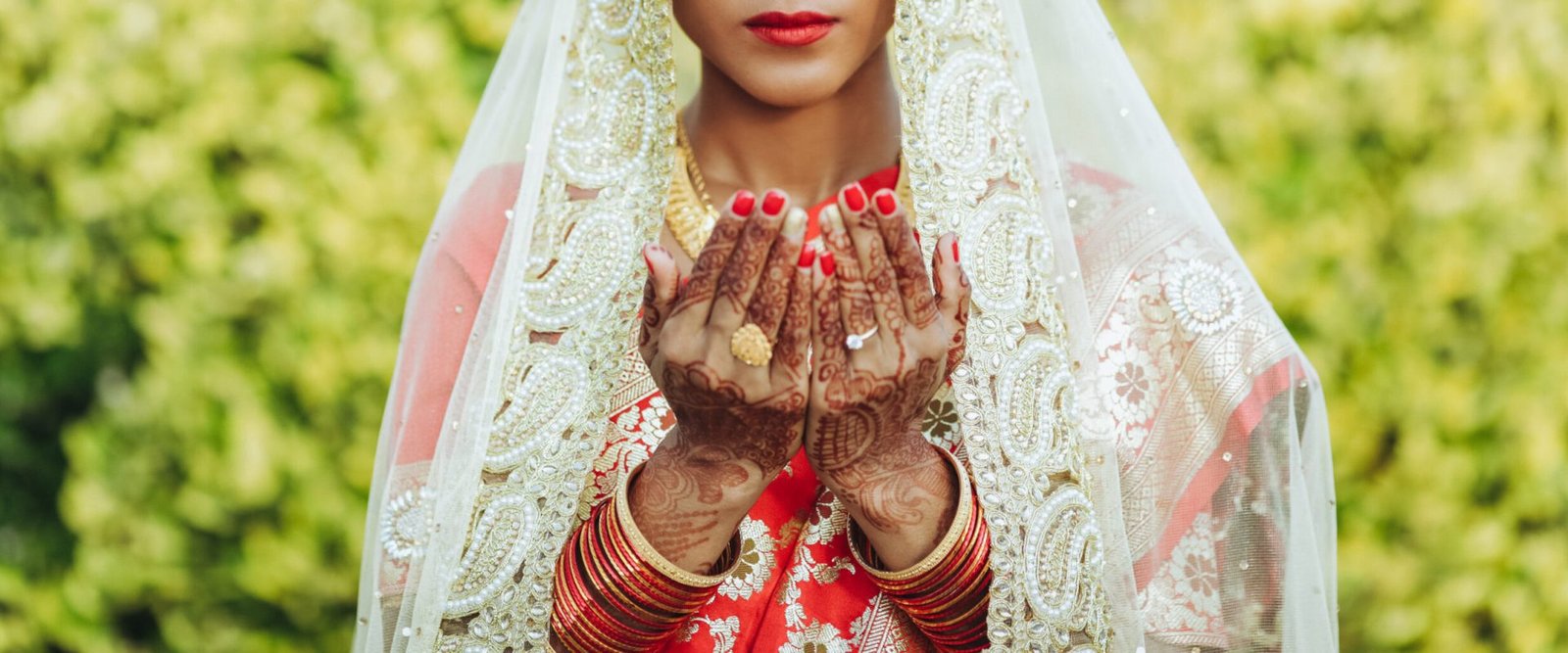 Hindu bride in white veil raises her hands up