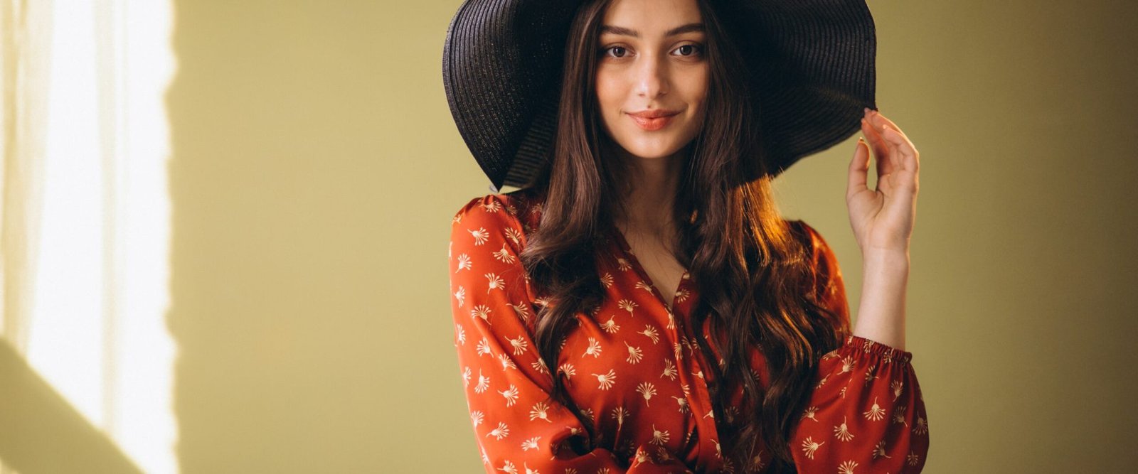 Young woman in a beautiful dress and hat in studio