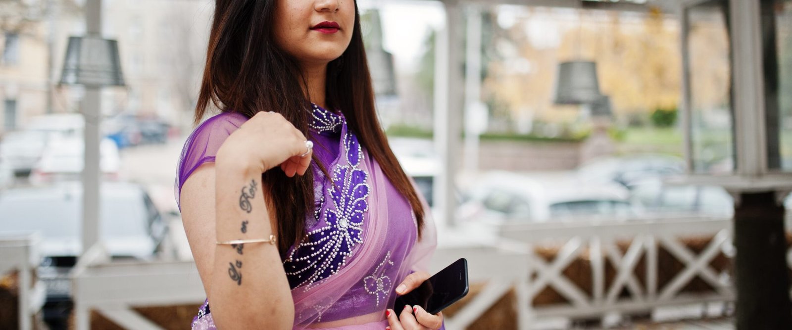 Indian hindu girl at traditional violet saree posed at street against wooden terrace.